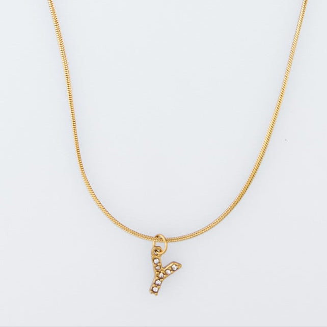 Gold necklace with a 'V' pendant on a light gray background